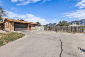 View of front of house with brick siding, a mountain view, a garage, asphalt driveway, and roof with shingles