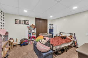 Bedroom with light carpet, a closet, recessed lighting, and a paneled ceiling