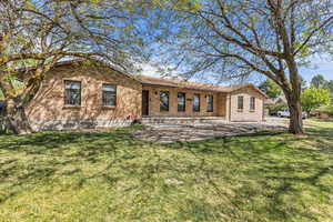 Back of property with a lawn, brick siding, and a patio area