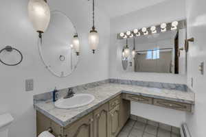 Full bath with vanity, a baseboard radiator, a shower, and light tile patterned floors