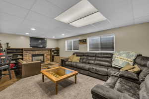 Living room featuring a drop ceiling, a fireplace, and wood finished floors