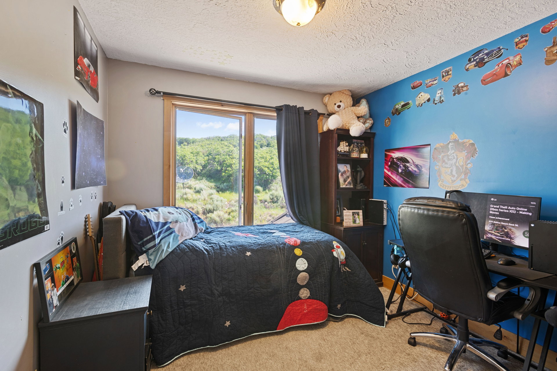 Bedroom with an office area, light carpet, and a textured ceiling