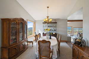 Dining room featuring suspended lighting, vaulted ceiling, and carpet floors