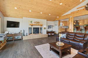 Living area with dark wood-type flooring, recessed lighting, a vaulted wooden ceiling, and a tile fireplace