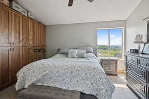 Bedroom with dark colored carpet, ceiling fan, and a textured ceiling