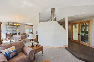 Living room featuring a chandelier, lofted ceiling, light carpet, and light wood-style flooring
