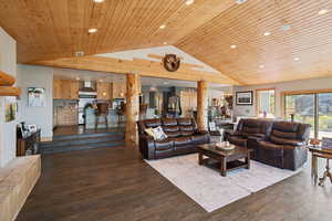 Living room with dark wood finished floors, a high wood ceiling, and recessed lighting