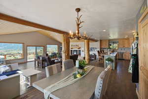Dining area with dark wood-style floors, hanging lights, a textured ceiling, and beamed ceiling