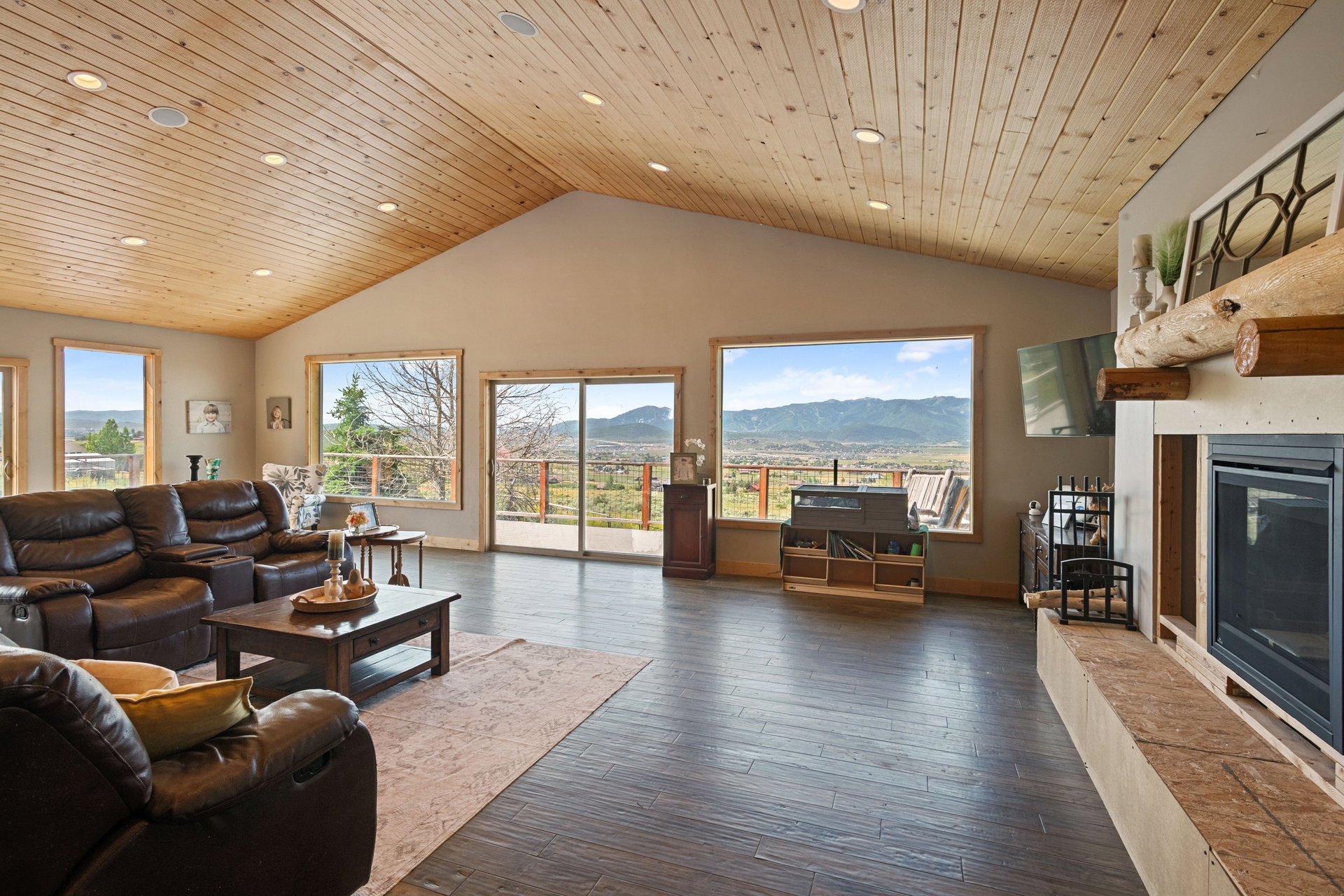 Living area featuring a glass covered fireplace, dark wood-style floors, plenty of natural light, and a high wood ceiling