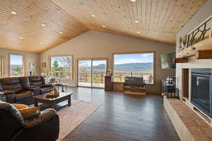 Living area featuring a glass covered fireplace, dark wood-style floors, plenty of natural light, and a high wood ceiling