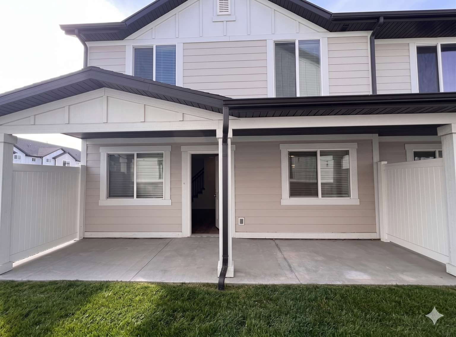 Covered concrete patio space featuring a partial privacy fence