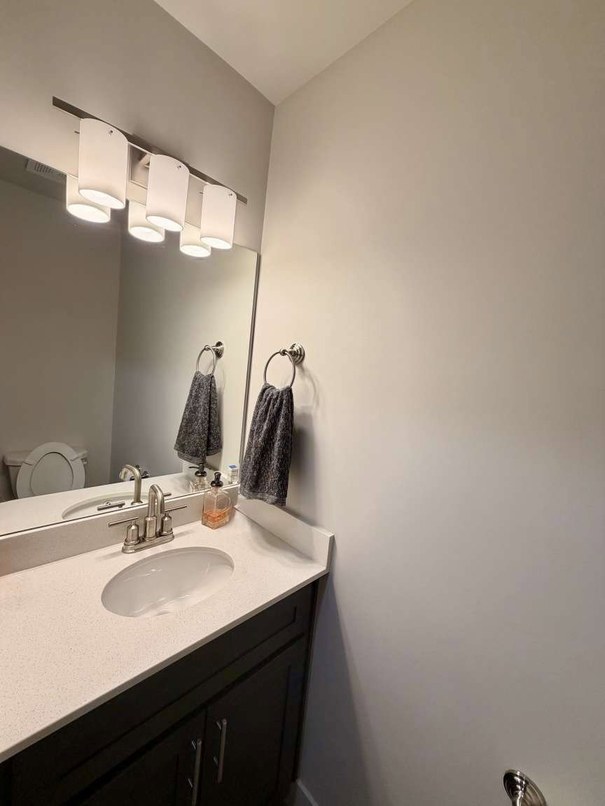 Bathroom vanity with a light-colored countertop, integrated sink, and brushed nickel faucet