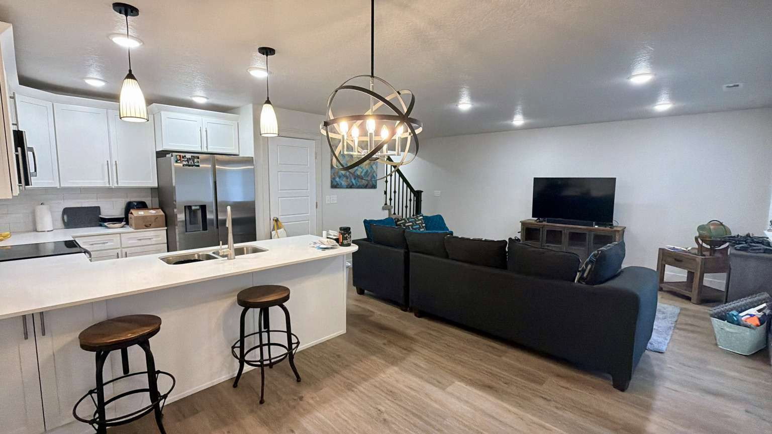 Open-concept living area featuring a kitchen with white cabinetry, stainless steel appliances, and a central island with bar seating