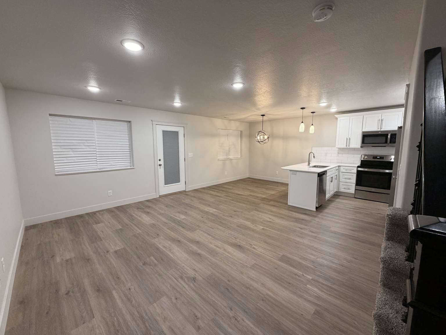 Open-concept living area featuring wood-finish flooring, recessed lighting, and a modern kitchen