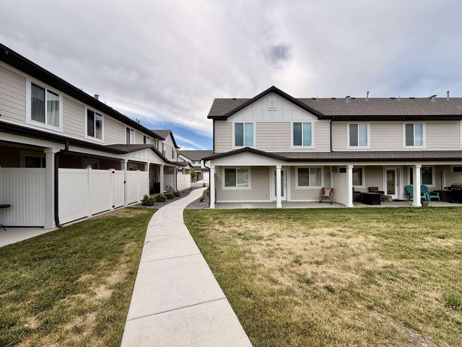 Multi-unit residential property featuring light-toned siding and dark shingle roofing