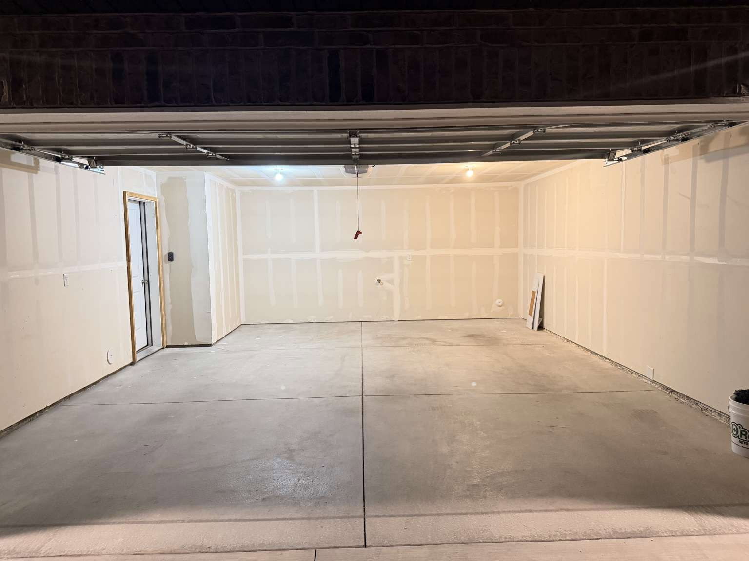 Spacious garage featuring a concrete floor, sheetrock walls, and an interior access door