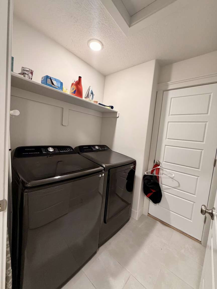 Dedicated laundry area featuring a white built-in shelf, recessed ceiling lighting, and light-toned tile flooring