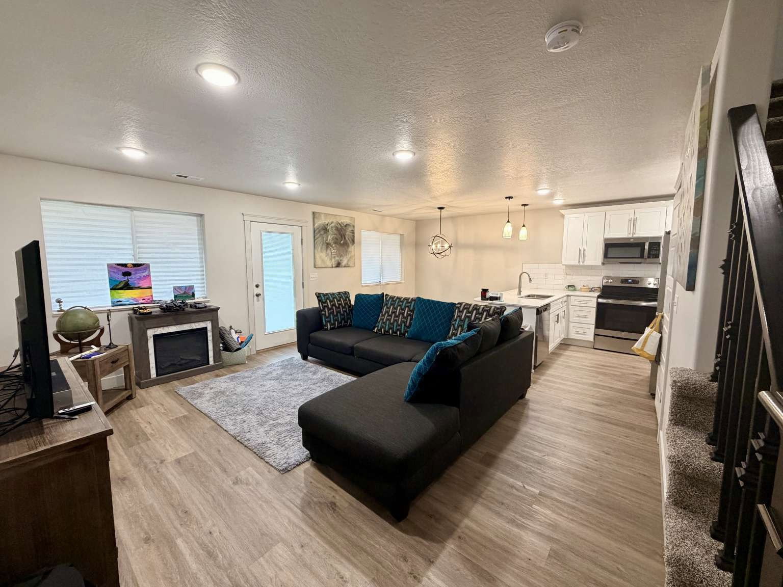 Open-concept living area with wood-finish flooring, recessed lighting, and a built-in electric fireplace