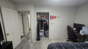 Bedroom featuring an office area, light wood-style flooring, and a closet