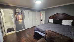 Bedroom featuring crown molding, dark wood-type flooring, connected bathroom, and a closet