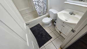 Bathroom featuring vanity, shower / bathtub combination with curtain, and light tile patterned flooring