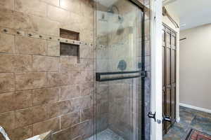 Bathroom featuring a shower stall and stone finish floors