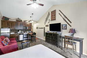 Living room with vaulted ceiling, a ceiling fan, and dark tile patterned floors