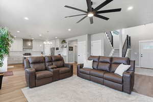 Living area with a ceiling fan, light wood-style floors, and a chandelier
