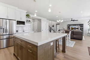 Kitchen with stainless steel fridge with ice dispenser, a center island, dual tone cabinetry, light wood-style floors, and open floor plan