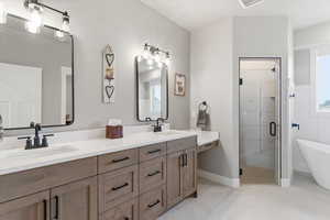 Full bath featuring a shower stall, double vanity, a soaking tub, and light tile patterned floors