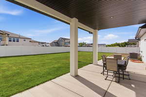 Fenced backyard with a patio area, outdoor dining space, and a residential view