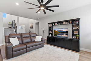 Living room with light wood-style floors, ceiling fan, and recessed lighting