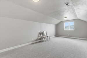 Additional living space with a textured ceiling and light colored carpet
