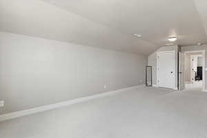 Bonus room featuring light colored carpet and vaulted ceiling