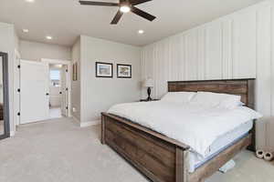 Bedroom with light colored carpet, a ceiling fan, recessed lighting, a decorative wall, and ensuite bathroom
