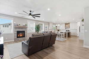 Living area with light wood finished floors, a fireplace, ceiling fan, and recessed lighting