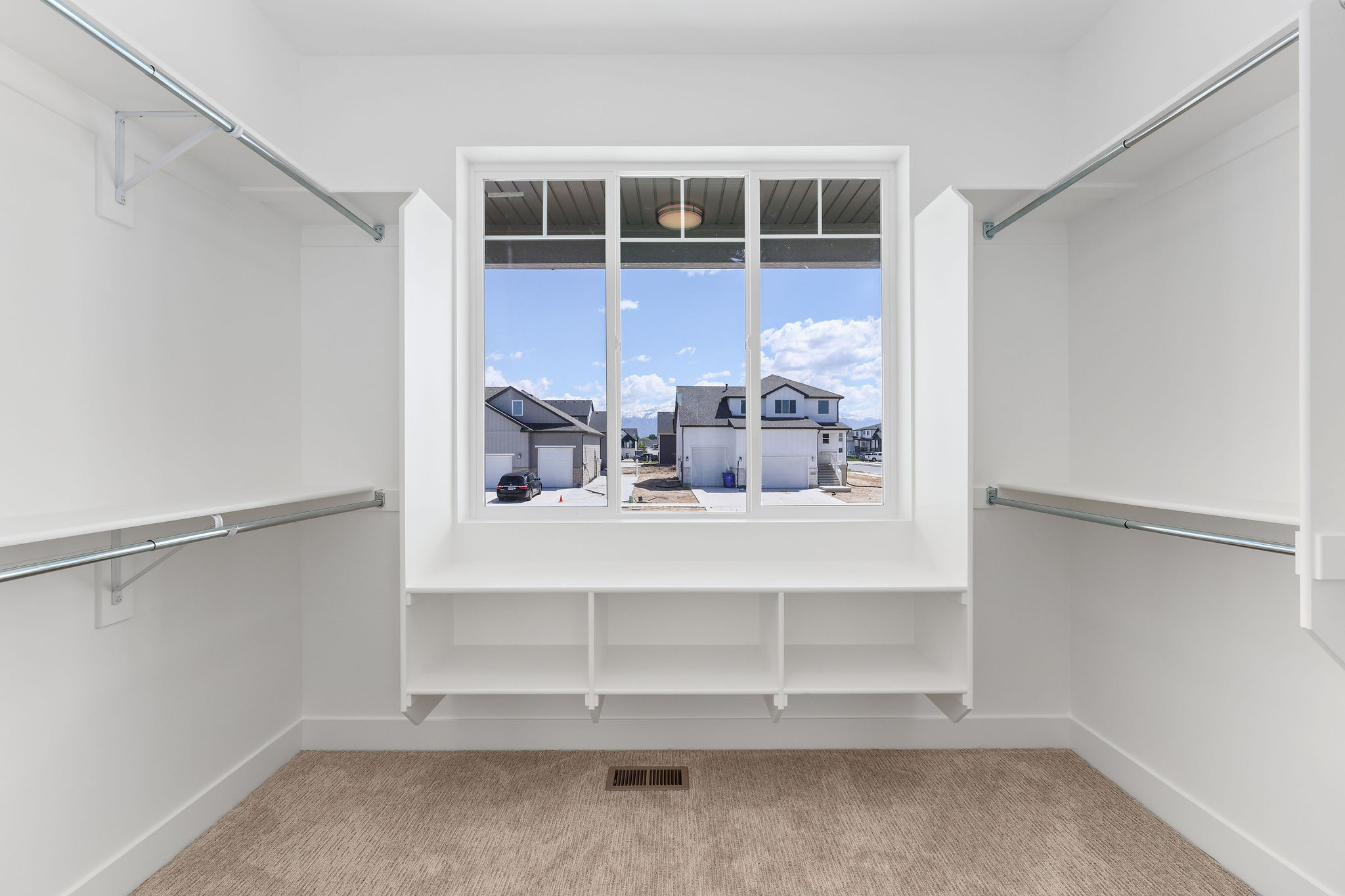 Spacious walk-in closet featuring built-in shelving, dual hanging rods, a window, and carpet flooring