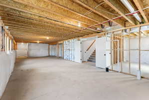 Unfinished basement with exposed ceiling joists and concrete flooring