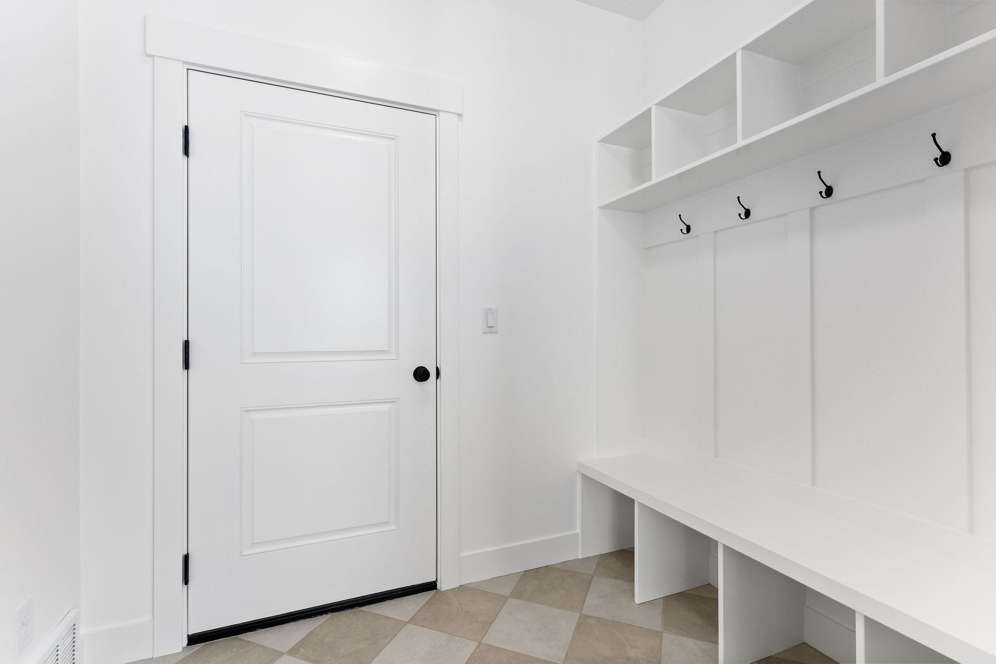 Entryway featuring built-in white storage cubbies, a bench, and a coat rack with black hooks