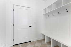 Entryway featuring built-in white storage cubbies, a bench, and a coat rack with black hooks