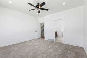 Spacious room featuring neutral carpeting, a ceiling fan with integrated lighting, recessed lighting, and crisp white walls