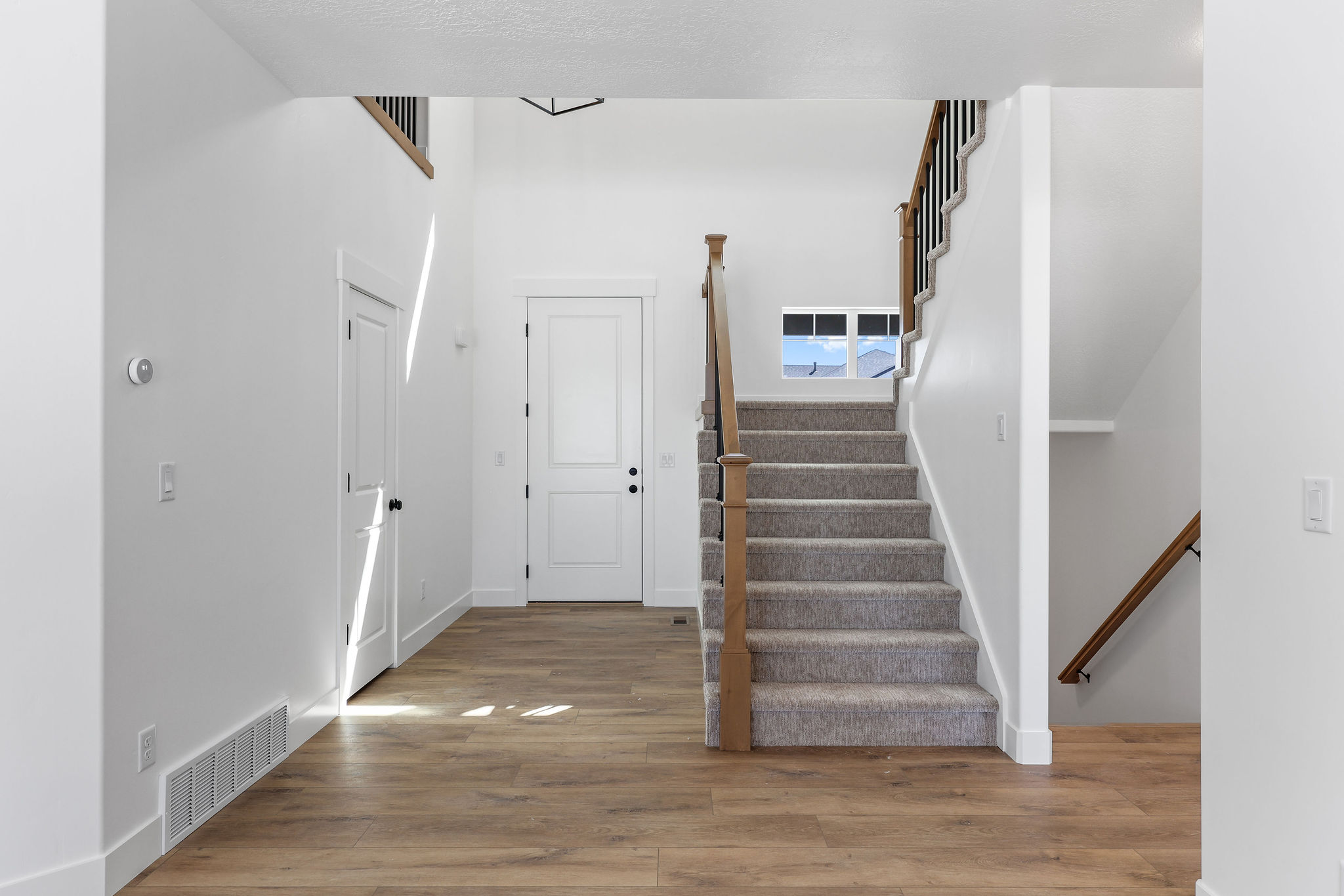 Entryway featuring wood-finish flooring and a carpeted staircase with wood and metal railings