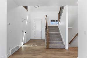 Entryway featuring wood-finish flooring and a carpeted staircase with wood and metal railings