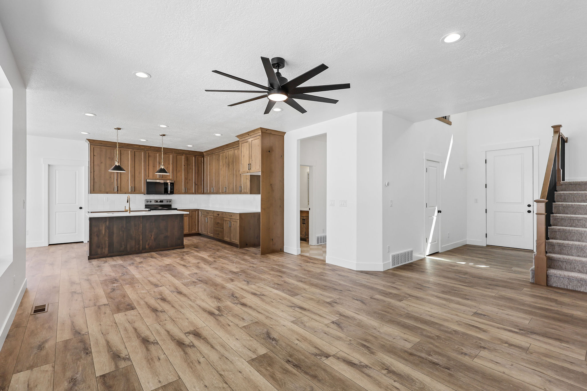Open-concept living space with wood-finish flooring, a contemporary ceiling fan, and recessed lighting