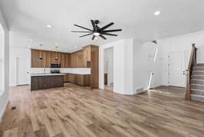 Open-concept living space with wood-finish flooring, a contemporary ceiling fan, and recessed lighting