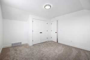 White walls and neutral carpeting define this interior space, featuring a double-door closet with black hardware