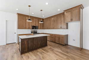 Kitchen featuring wood-finish flooring and a central island with a built-in sink and gold-tone faucet