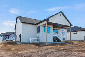 Rear exterior featuring a covered patio, multiple windows, and an exterior staircase with white railings