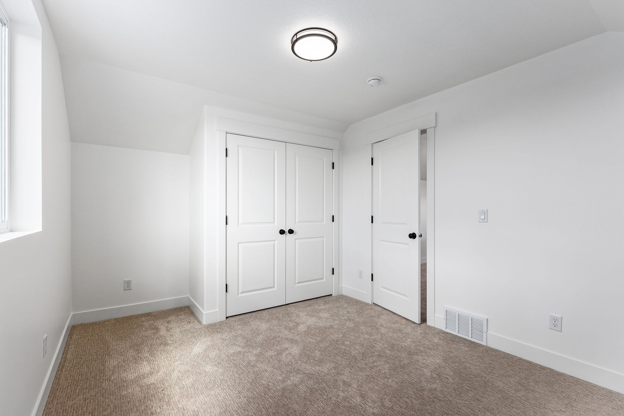 Bedroom featuring plush carpet flooring, white painted walls, a built-in closet with bifold doors, and a window for natural light