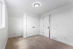 Bedroom featuring plush carpet flooring, white painted walls, a built-in closet with bifold doors, and a window for natural light